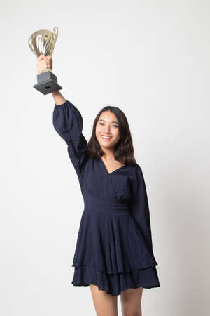 Successful young asian woman holding a trophy on white backgroundの写真素材
