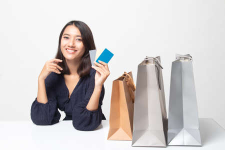Young Asian woman with shopping bag and blank card on white backgroundの写真素材