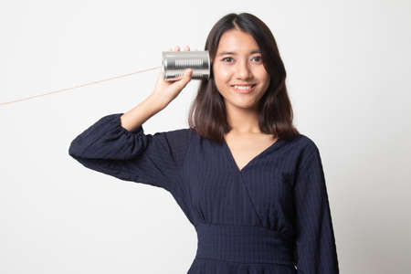 Young Asian woman with tin can phone on white backgroundの写真素材