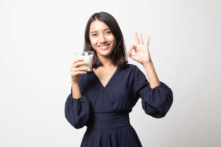 Healthy Asian woman drinking a glass of milk show OK sign on white backgroundの写真素材