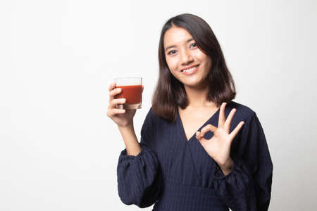 Young Asian woman show OK with tomato juice on white backgroundの写真素材
