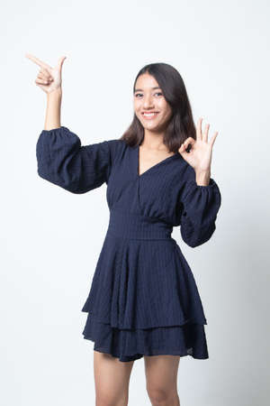 Young Asian woman point and show OK on white backgroundの写真素材