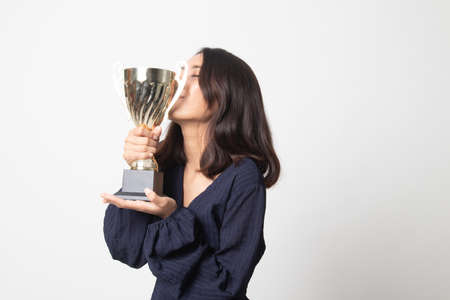 Successful young asian woman holding kissing a trophy on white backgroundの写真素材