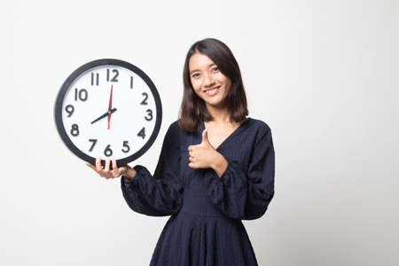Young Asian woman thumbs up with a clock on white backgroundの写真素材