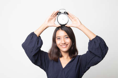 Young Asian woman with a clock on white backgroundの写真素材