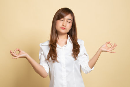 Concentrated relaxed  asian  female  closed eyes, having relaxation while meditating, trying to find balance and harmony Yoga and meditation concept on beige backgroundの写真素材