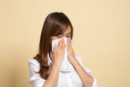 Young Asian woman got sick and flu on beige backgroundの写真素材