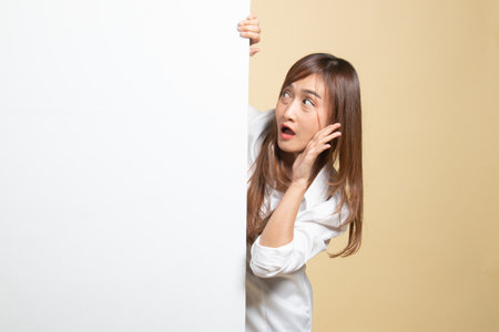 Excited young Asian woman with blank sign on beige backgroundの写真素材