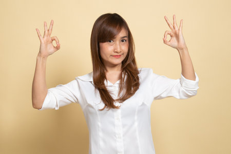 Asian woman show double OK hand sign  and smile on beige backgroundの写真素材