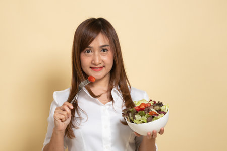 Healthy Asian woman with salad on beige backgroundの写真素材