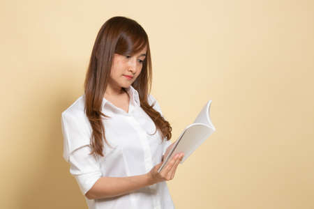 Young Asian woman read a book on beige backgroundの写真素材