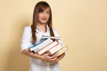 Young Asian woman studying  with may books on beige background