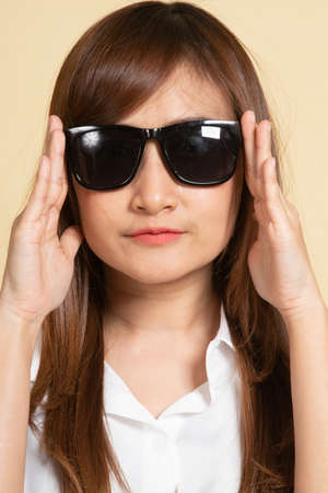 Portrait of a beautiful young asian girl in sunglasses on beige backgroundの写真素材