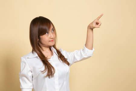 Asian woman touching the screen with her finger on beige backgroundの写真素材
