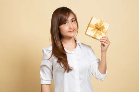 Young Asian woman with a gift box on beige backgroundの写真素材