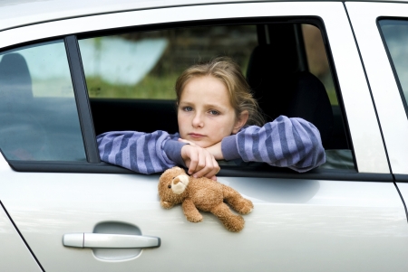 Little girl in car is going to miss her friends.の写真素材