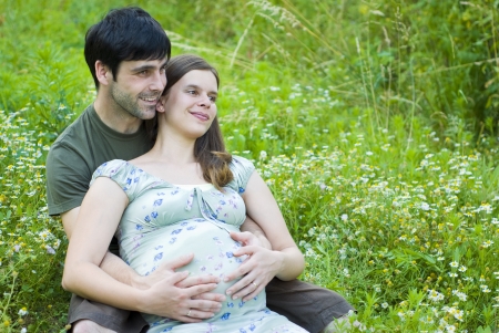 Husband with pregnant wife is resting in nature.の写真素材