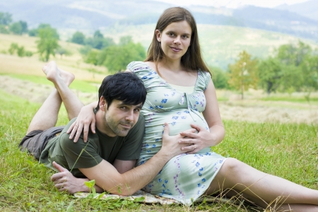 Husband with pregnant wife is resting in nature.の写真素材