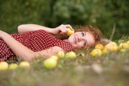 Girl with apple is lying in the garden.の写真素材