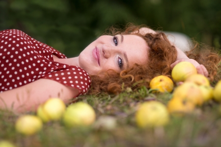 Girl with apple is lying in the garden.の写真素材