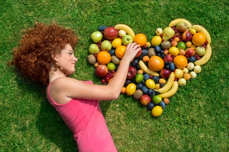 Girl with fruit lying on the grassの写真素材