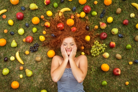 Girl with fruit lying on the grassの写真素材
