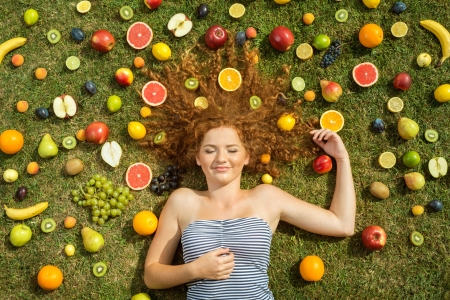 Girl with fruit lying on the grassの写真素材