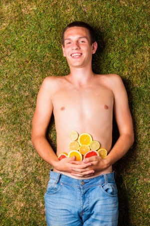 Man with fruit is lying on the grassの写真素材