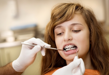 Teenage girl with the braces on her teeth is having a treatment at dentistの写真素材