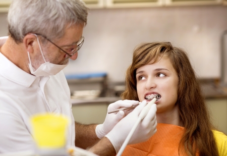Teenage girl with the braces on her teeth is having a treatment at dentistの写真素材