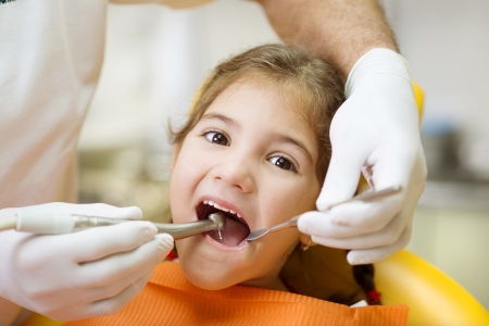 Little girl is having her teeth examined by dentistの写真素材