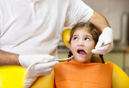 Little girl is having her teeth checked by dentistの写真素材