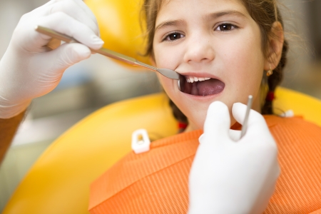 Little girl is having her teeth checked by dentistの写真素材