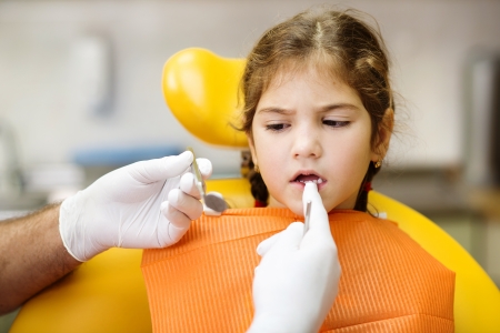 Little girl is having her teeth checked by dentistの写真素材