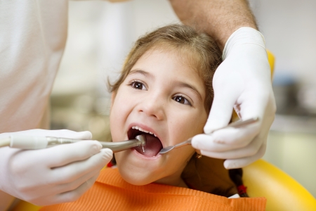Little girl is having her teeth checked by dentistの写真素材