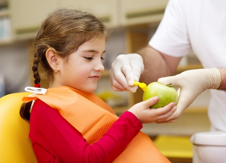 Dentist is showing the technique of teeth cleaning to a little girlの写真素材