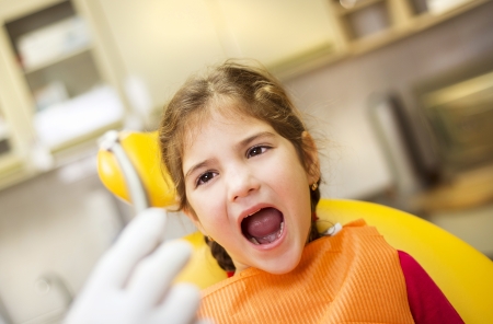 Little girl is having her teeth checked by dentistの写真素材