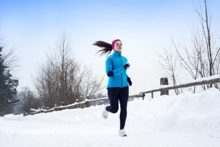 Athlete woman is running during winter training outside in cold snow weather.の写真素材