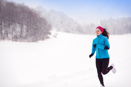 Athlete woman is running during winter training outside in cold snow weather の写真素材