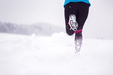 Athlete woman is running during winter training outside in cold snow weather の写真素材