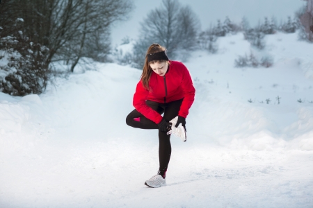 Athlete woman is running during winter training outside in cold snow weather の写真素材