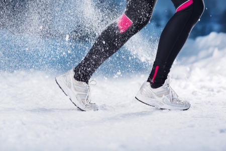 Athlete woman is running during winter training outside in cold snow weather の写真素材