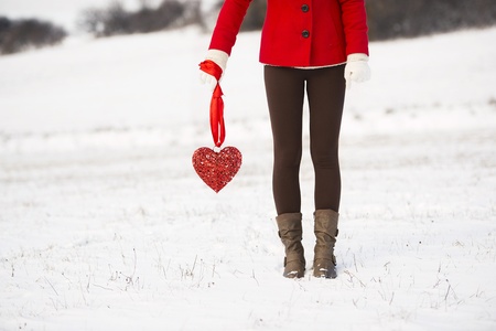 Lonely girl in the red coat is holding a red heart and waiting の写真素材