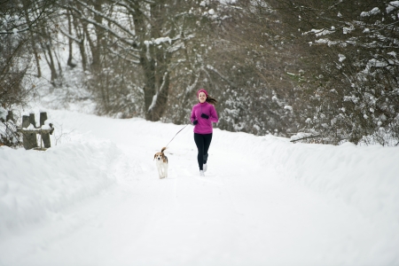 Athlete woman is running during winter training outside in cold snow weather.の写真素材