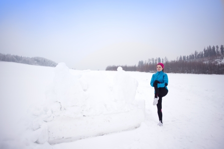Athlete woman is running during winter training outside in cold snow weather.の写真素材