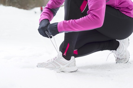 Athlete woman is running during winter training outside in cold snow weather.の写真素材