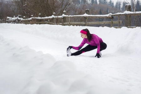 Athlete woman is running during winter training outside in cold snow weather.の写真素材
