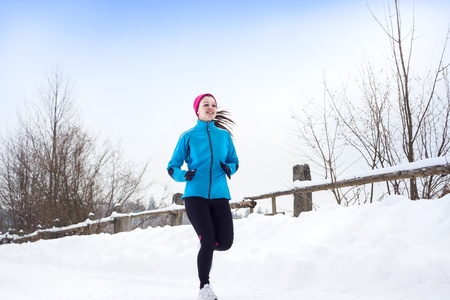 Athlete woman is running during winter training outside in cold snow weather.の写真素材