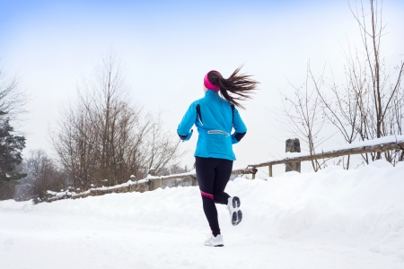 Athlete woman is running during winter training outside in cold snow weather.の写真素材