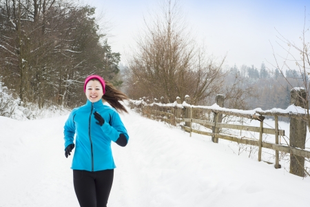 Athlete woman is running during winter training outside in cold snow weather.の写真素材